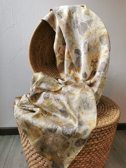 leaf eco-printed silk scarf draped over a woven basket on a light grey background