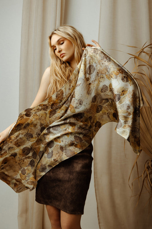 Woman holding a patterned scarf in front of a neutral background