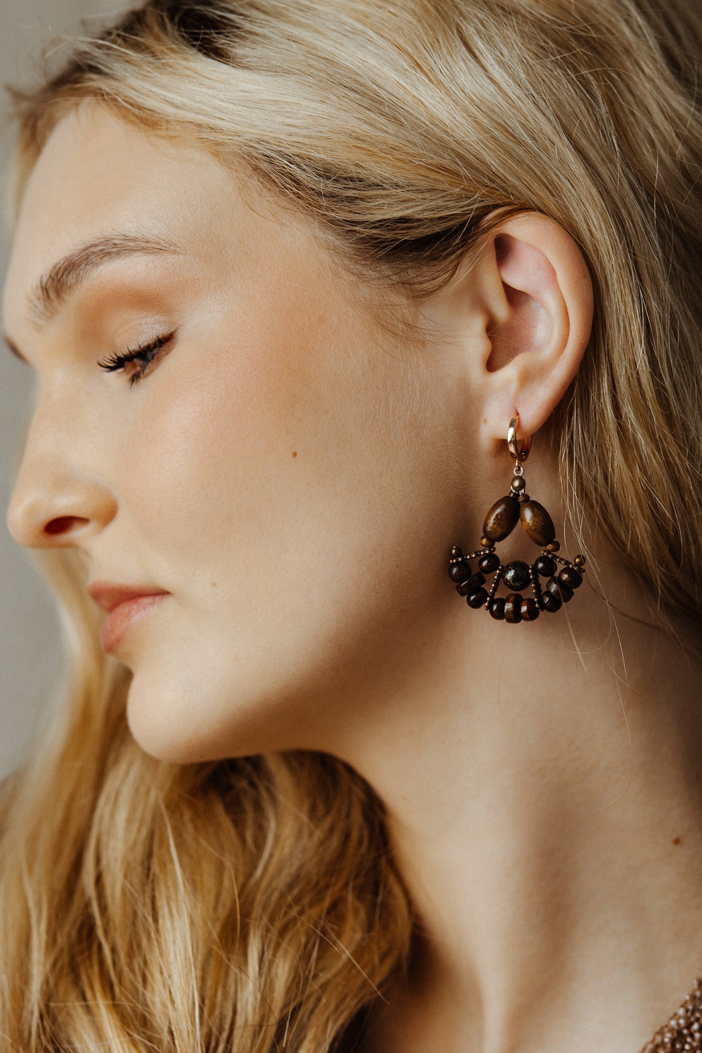 Close-up of a woman wearing a decorative earring with a neutral background