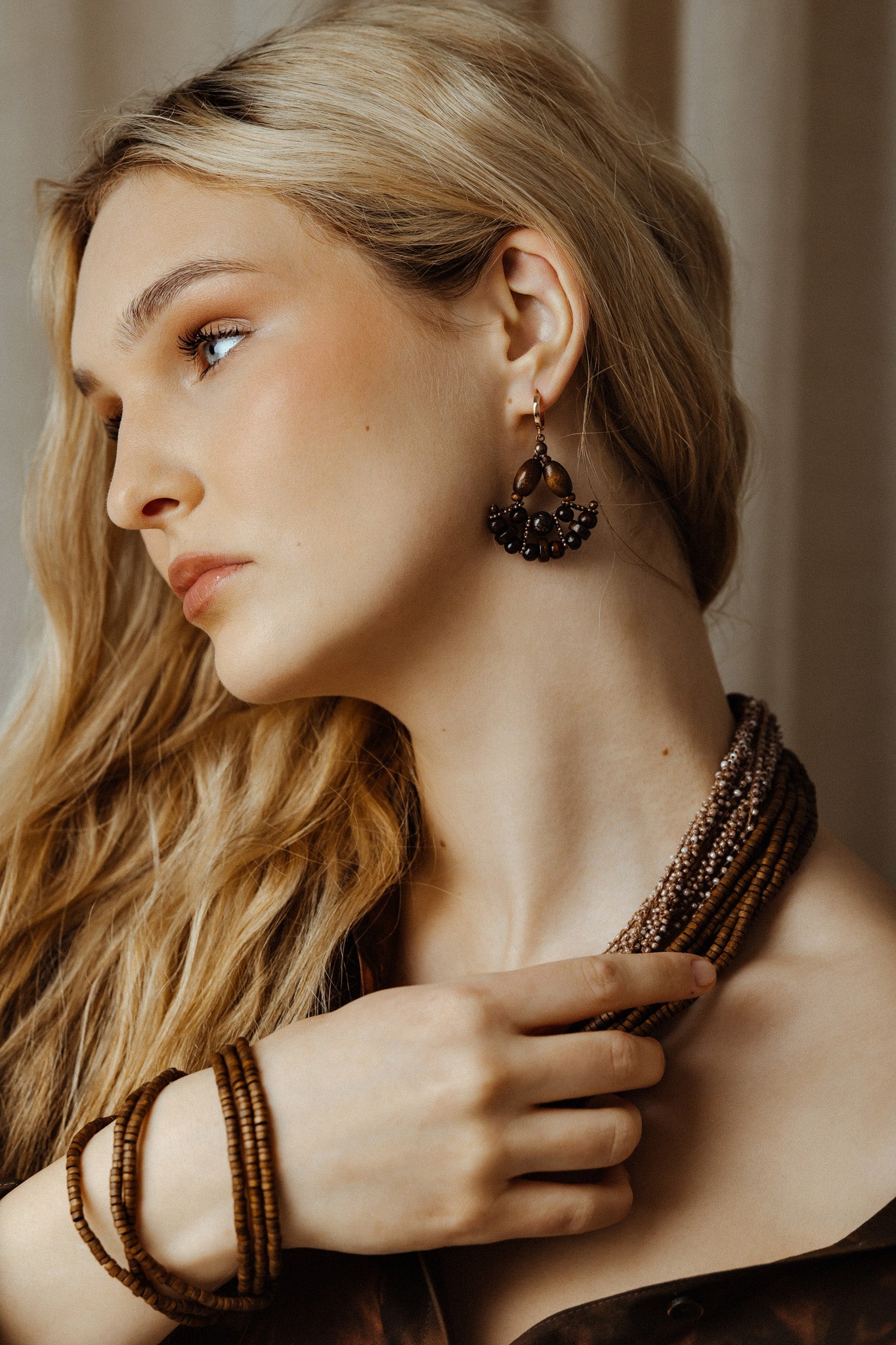 Woman wearing a beaded necklace and earrings with a neutral background