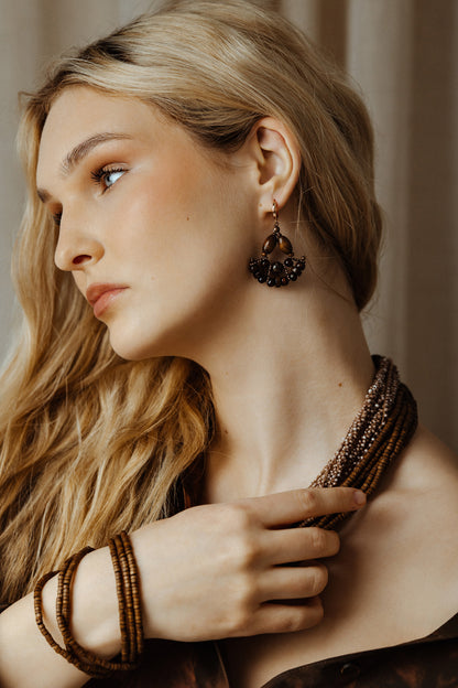 Woman wearing a beaded necklace and earrings with a neutral background