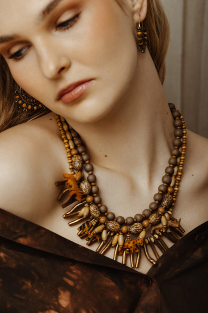 Close-up of a model wearing wild animal charm necklace and earrings with a neutral background
