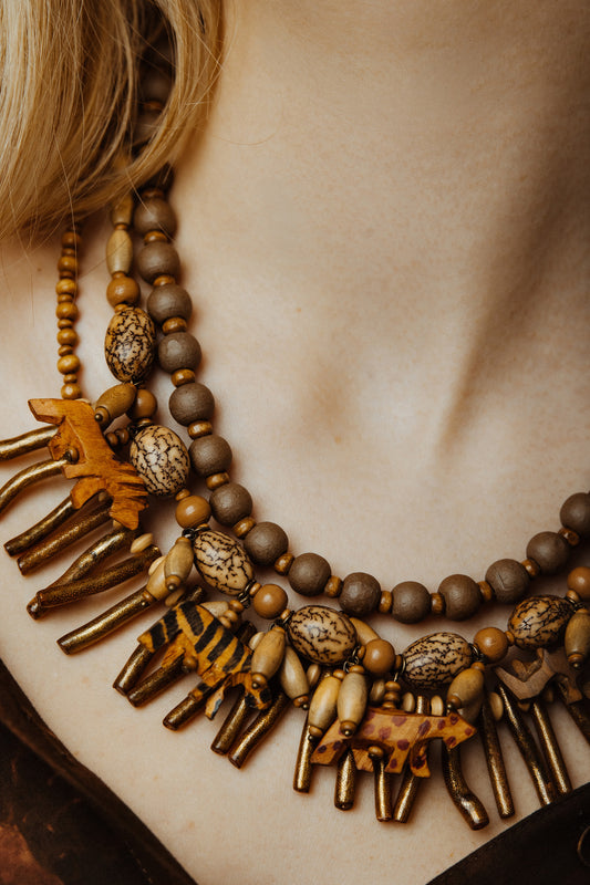 Close-up of a person wearing a detailed necklace with beads and metal elements.