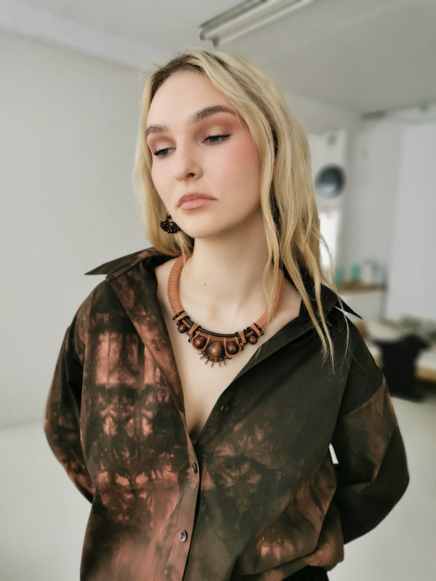 Woman wearing a patterned shirt and boho leather necklace indoors