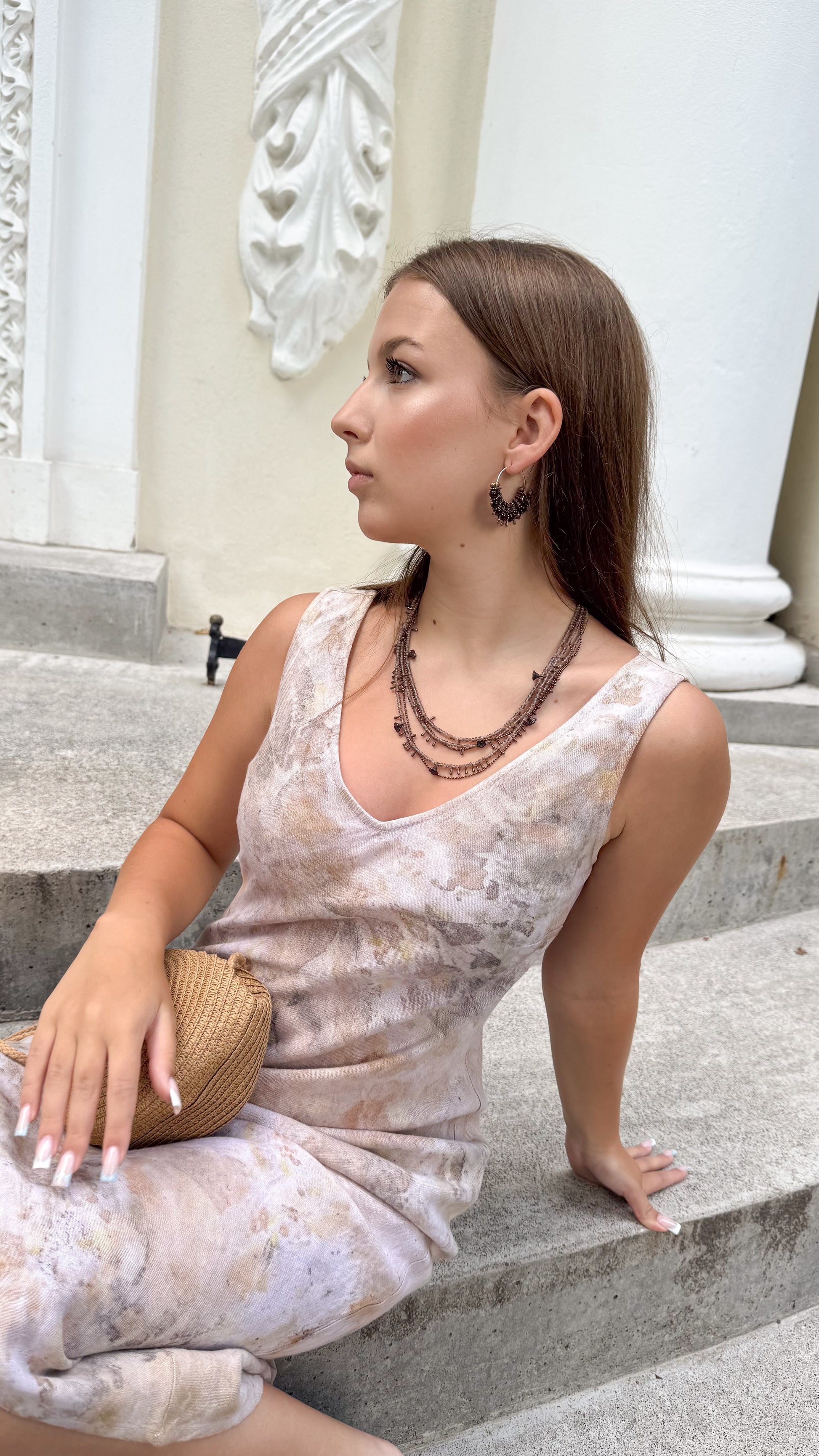 girl wearing beige linen dress and multilayer  seed bead necklace