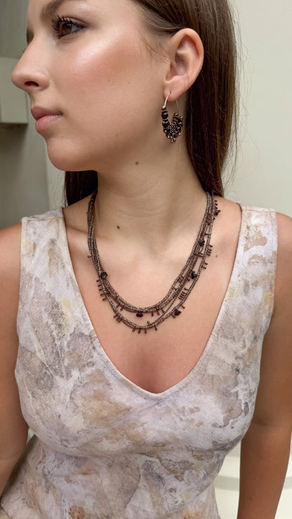 girl wearing beige linen dress and multilayer  seed bead necklace
