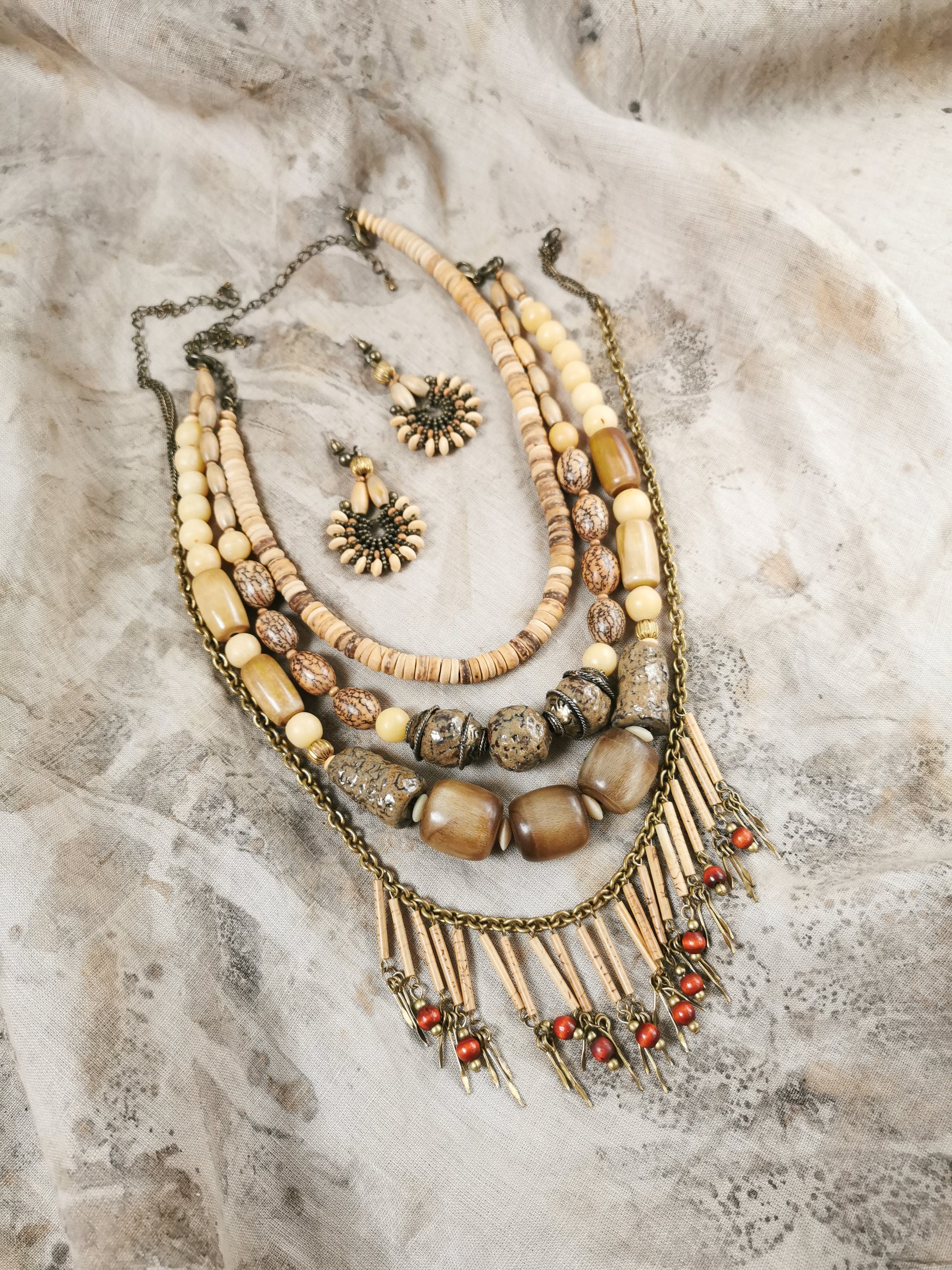 Bone bead Jewelry set with necklaces and earrings on a textured surface