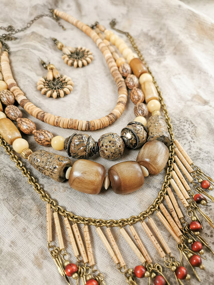 Collection of beaded necklaces and earrings on a textured fabric background
