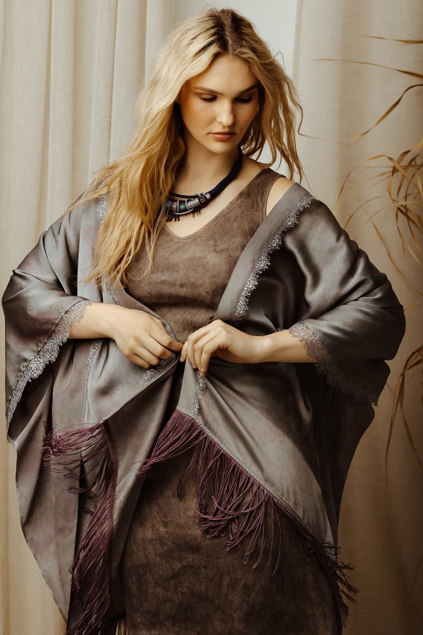 Woman wearing a brown dress with silk robe against a neutral background