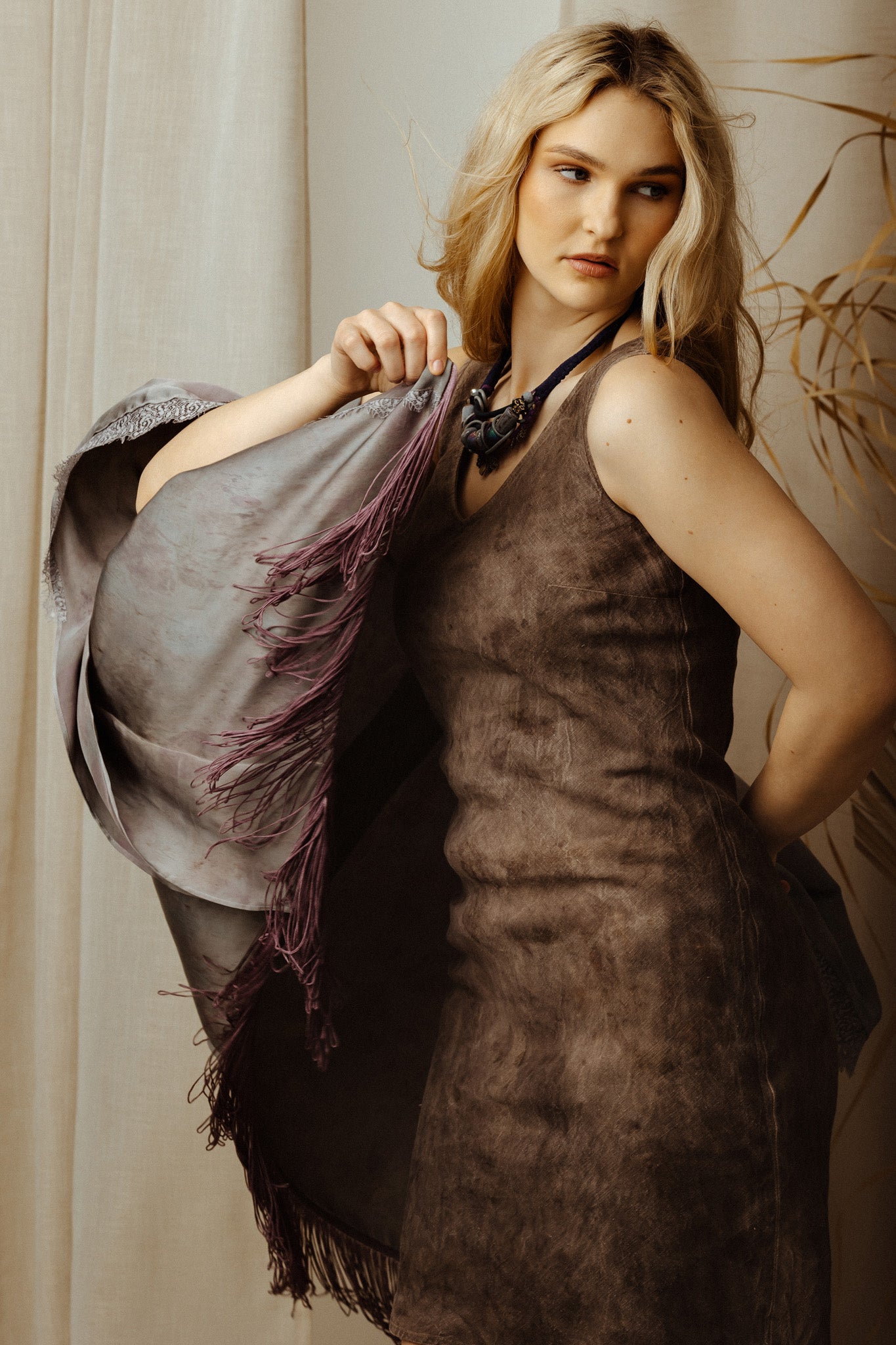 Woman holding a purple silk robe against a neutral background