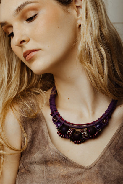 Woman wearing a purple beaded necklace with a neutral background