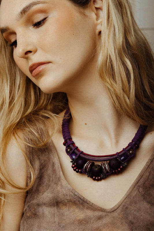Woman wearing a purple beaded necklace with a neutral background