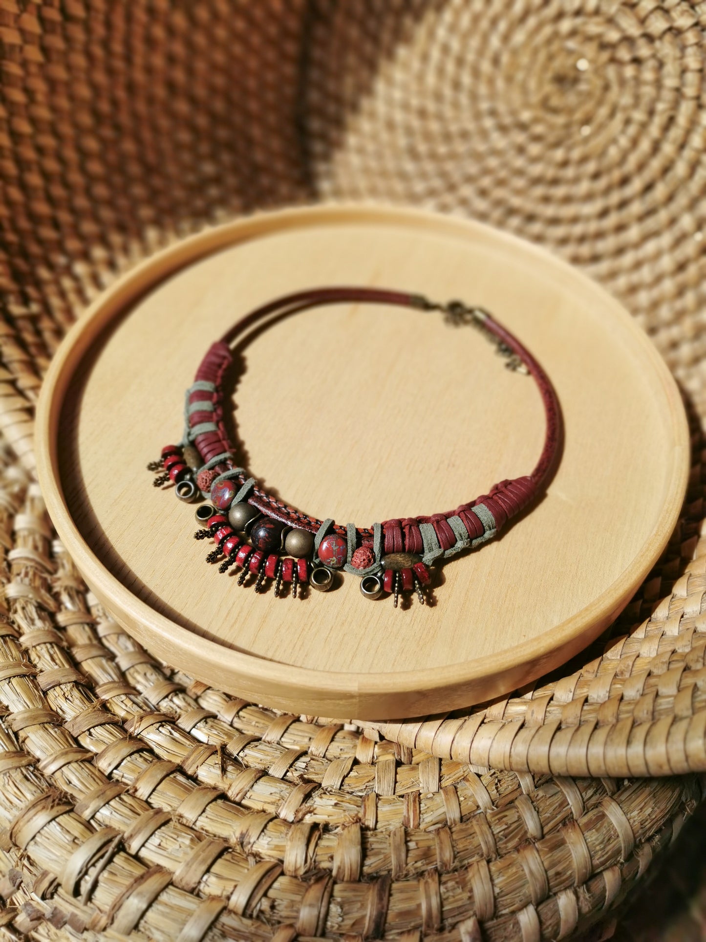 Necklace with red and black beads on a wooden stand with woven background