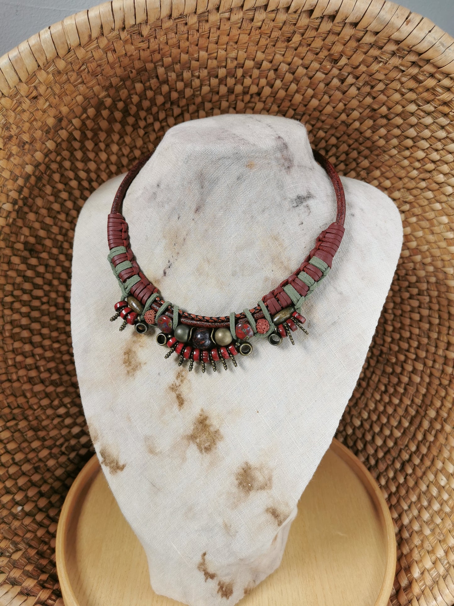 Necklace with red and gold beads on a white stone with a woven basket background