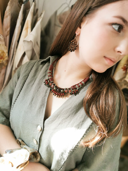 Woman wearing a large beaded necklace with a neutral background