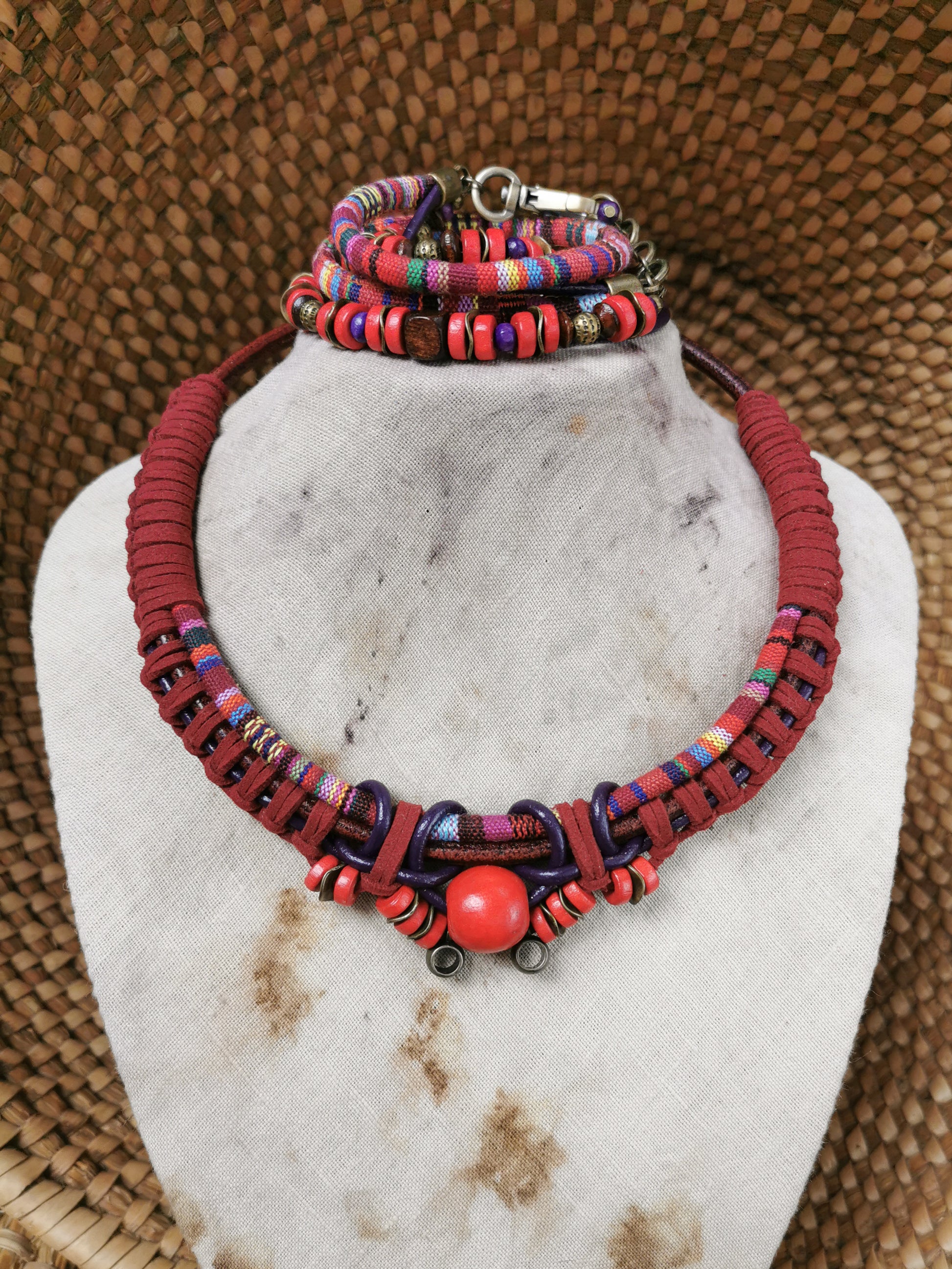 Colorful beaded necklace and bracelet set on a white marble stand with a textured brown background