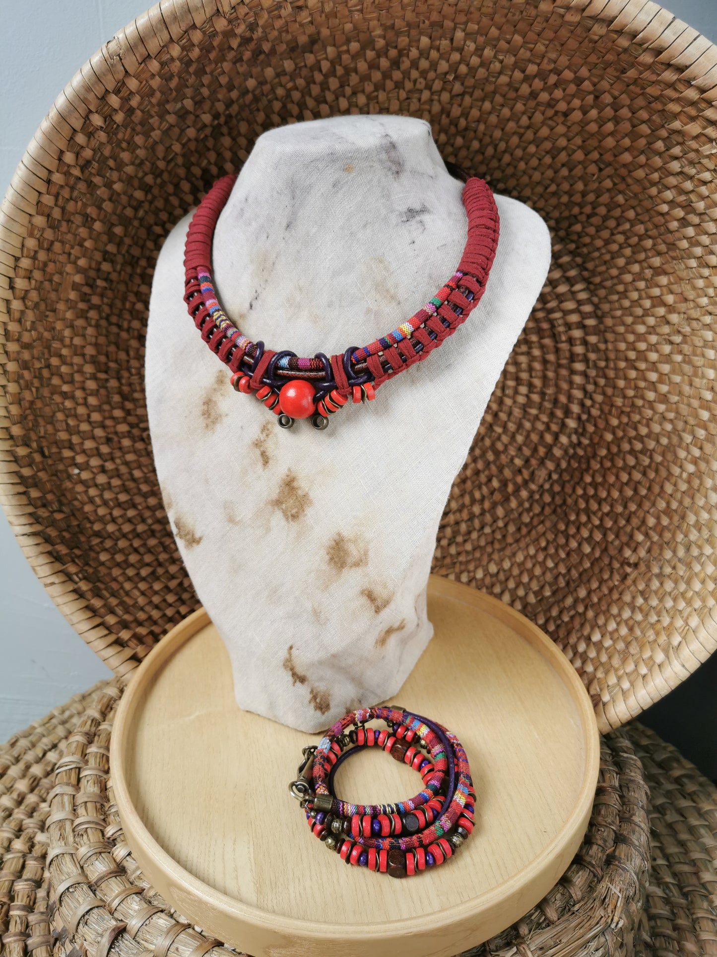 Red and black beaded necklace on a marble stand with a woven basket background