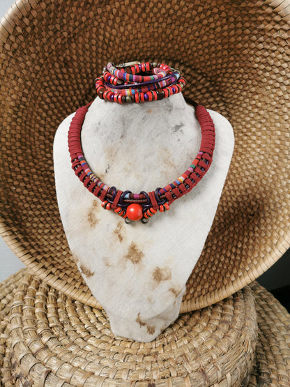 Red beaded necklace and bracelets on a white stone stand with a woven background