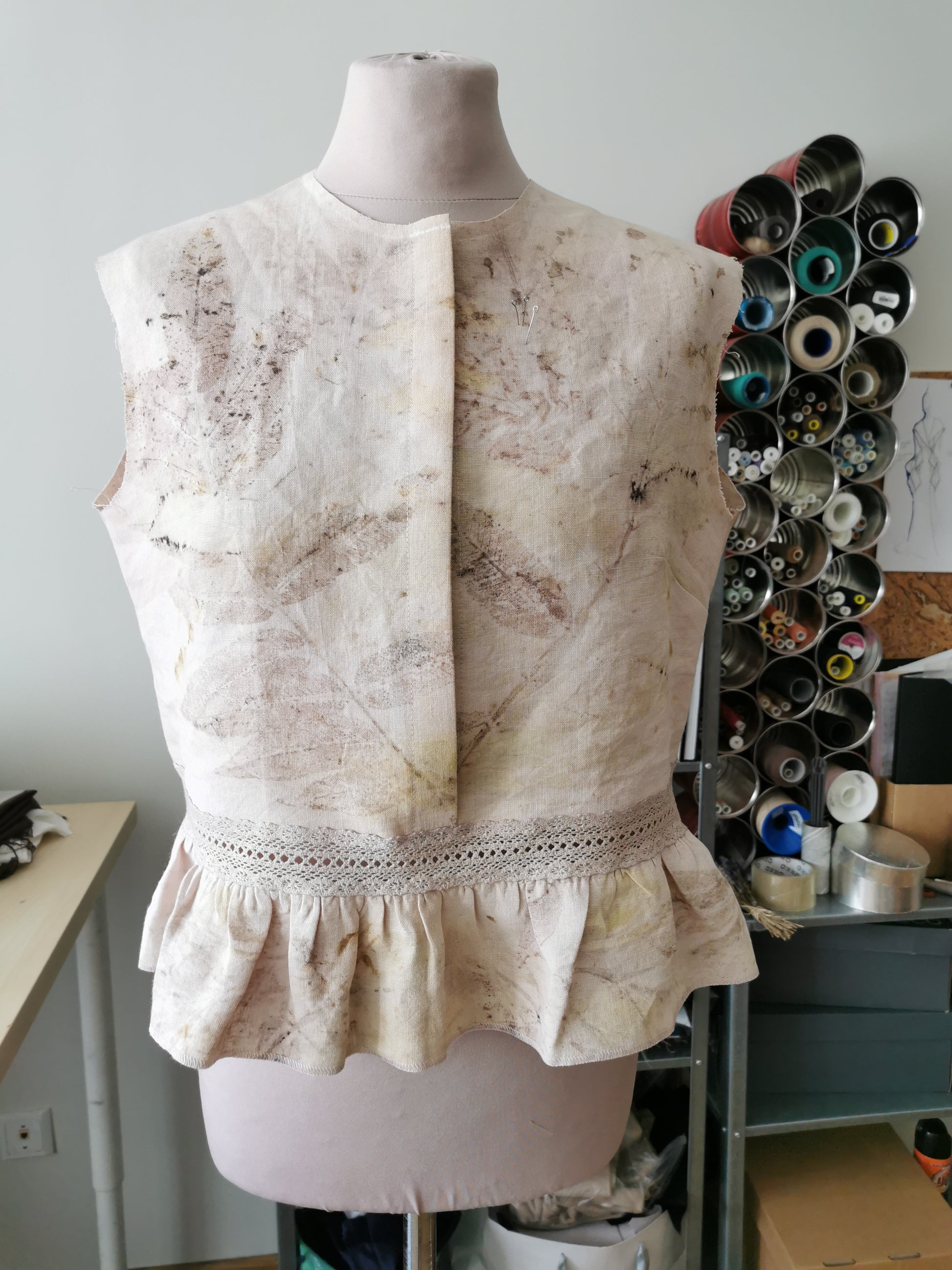 White lace top on a mannequin with a shelf of spools in the background