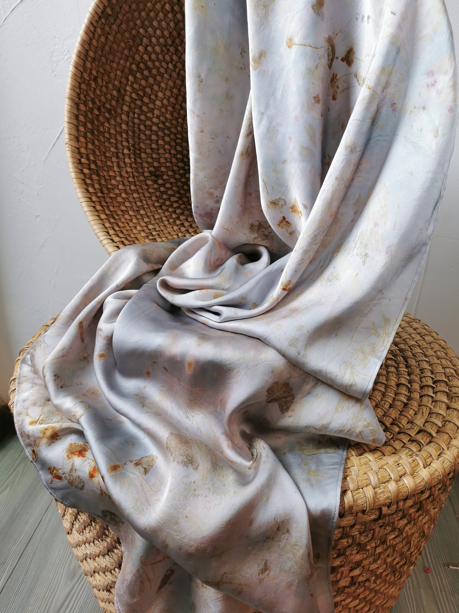 silver botanical dye silk shawl with brown spots on a woven chair.