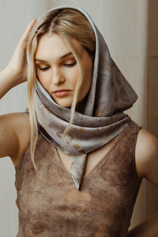 Woman wearing a patterned scarf on her head with a neutral background
