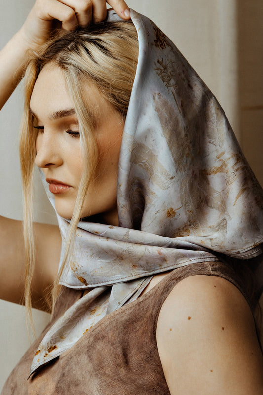 Woman wearing a patterned scarf on her head with a neutral background