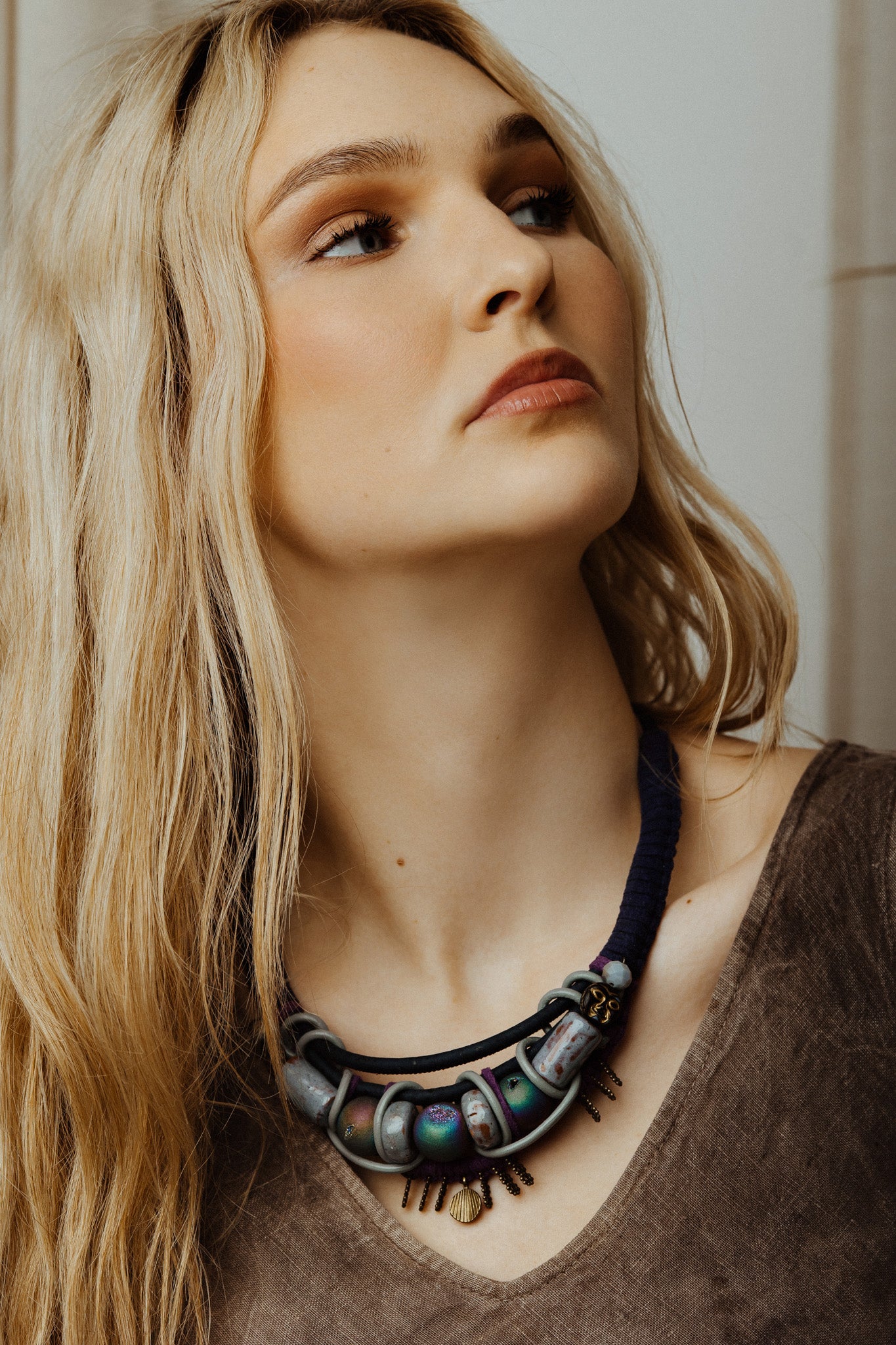 Woman wearing a detailed necklace with a neutral background