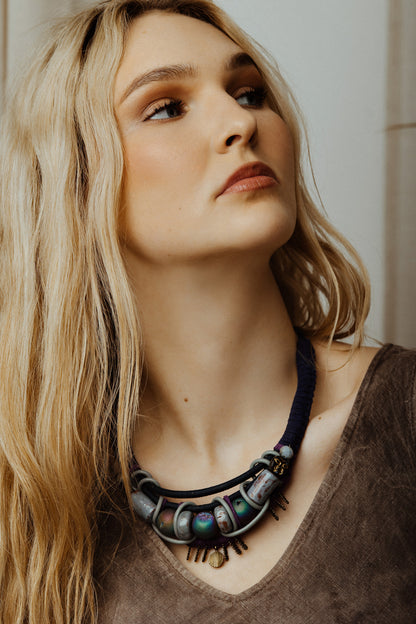 Woman wearing a detailed necklace with a neutral background