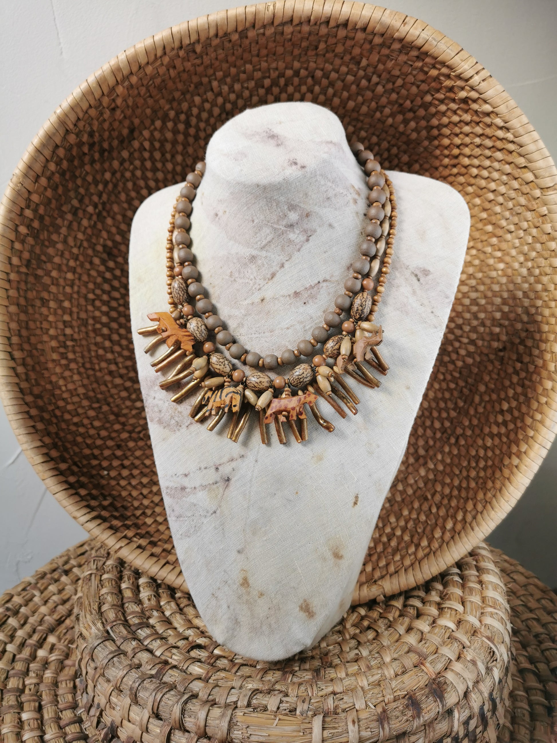 statement wild animal charm necklace displayed on a marble bust with a woven basket background