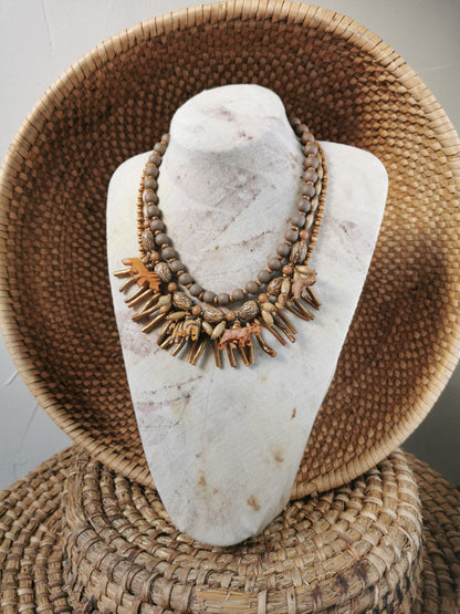 statement wild animal charm necklace displayed on a marble bust with a woven basket background