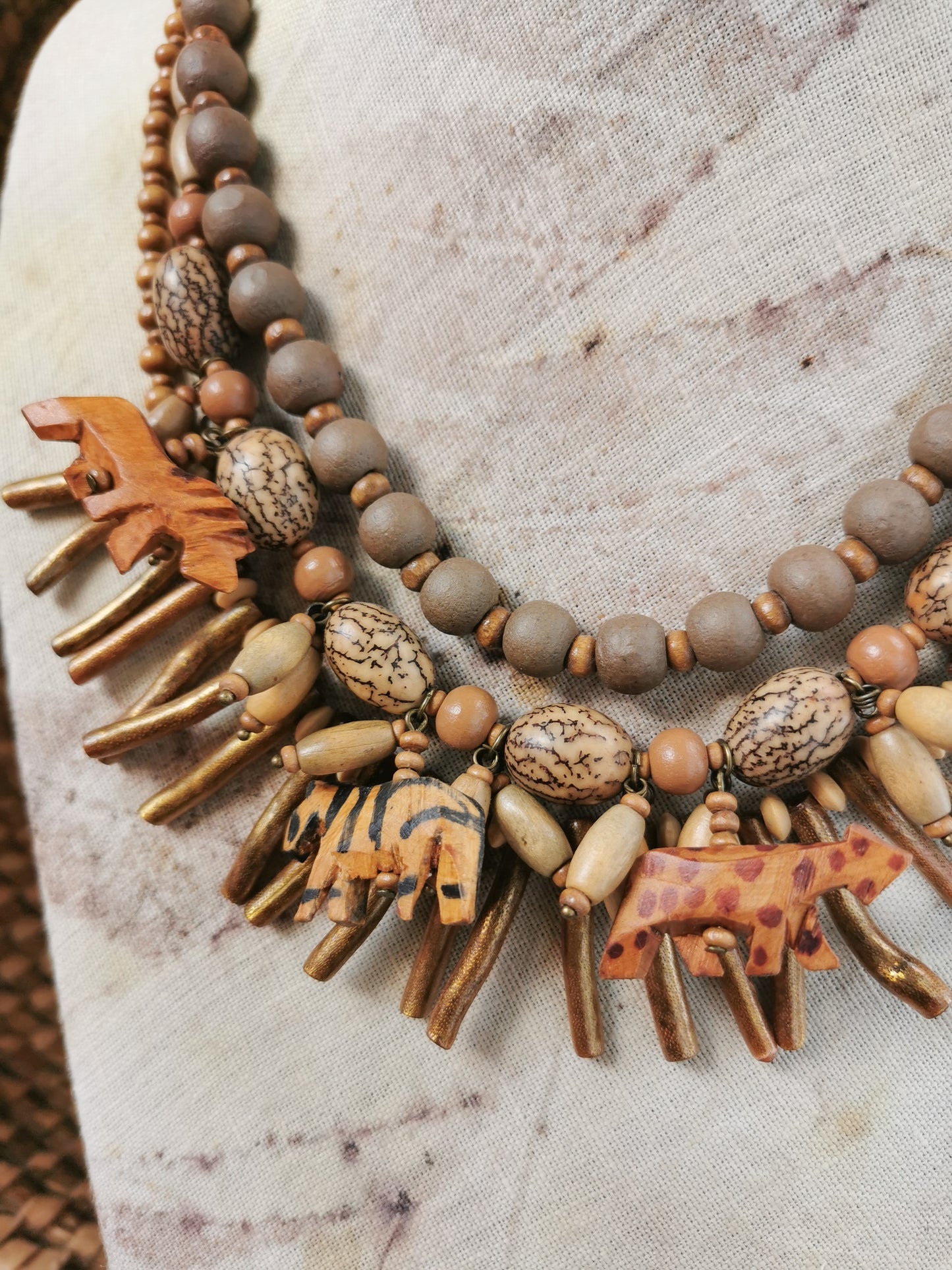 statement wild animal charm necklace with wooden and metal beads on a textured surface