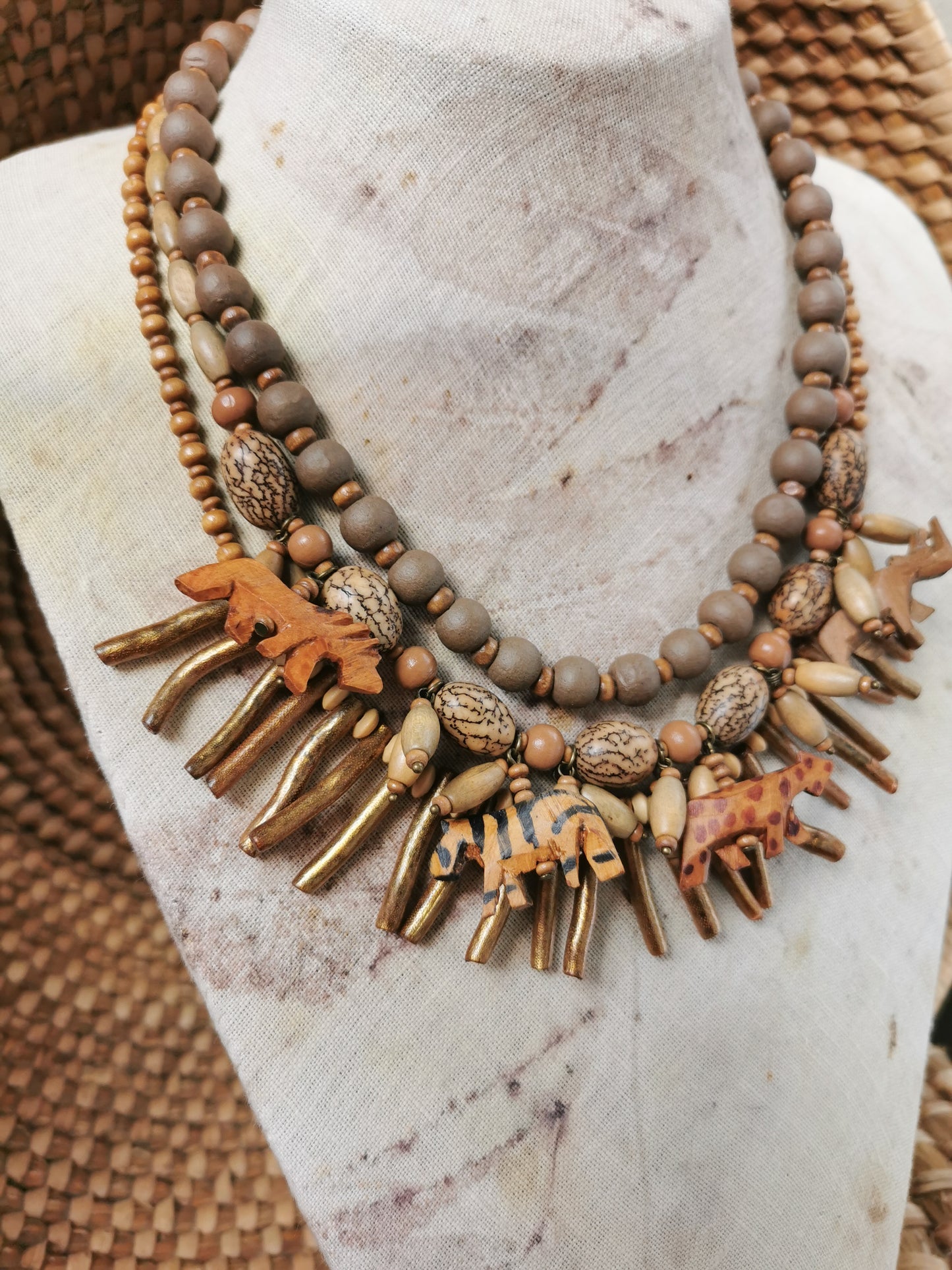 statement wild animal charm necklace with wooden and metal beads on a mannequin bust.