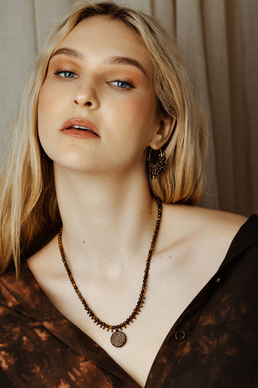 Woman wearing a beaded necklace with a neutral background