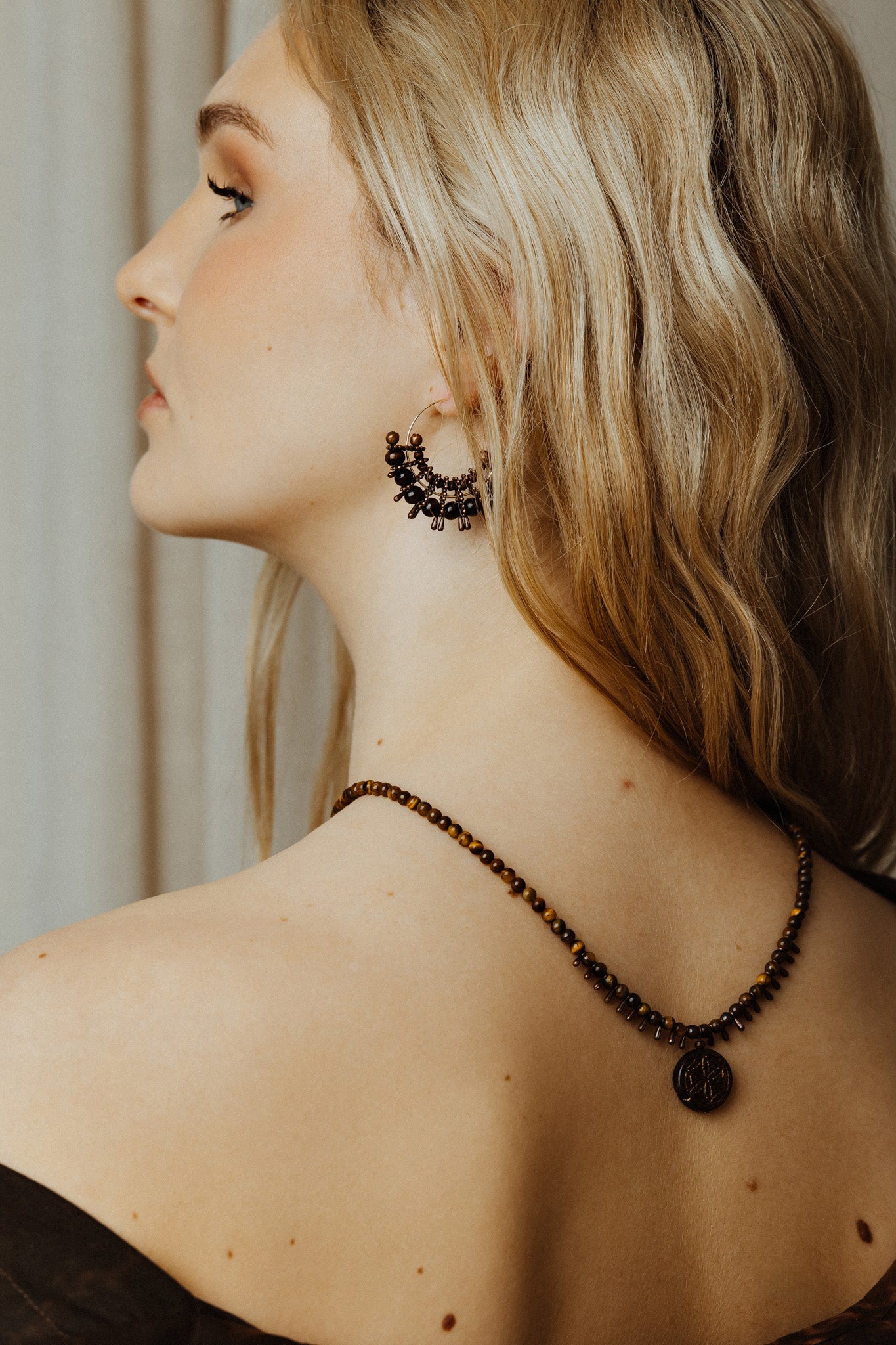 Woman wearing a necklace and earrings with a neutral background