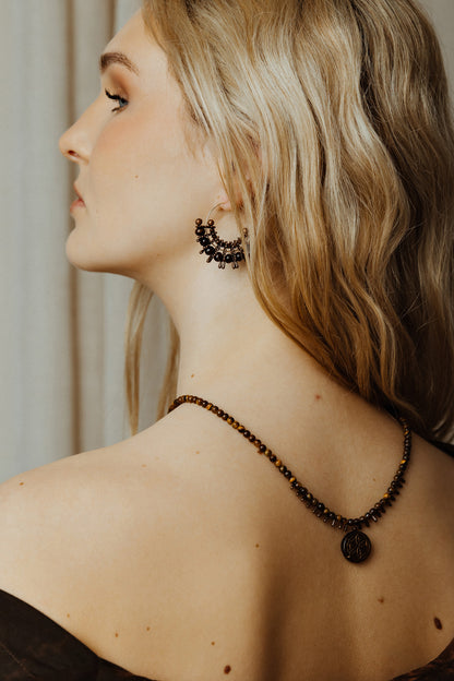 Woman wearing a necklace and earrings with a neutral background