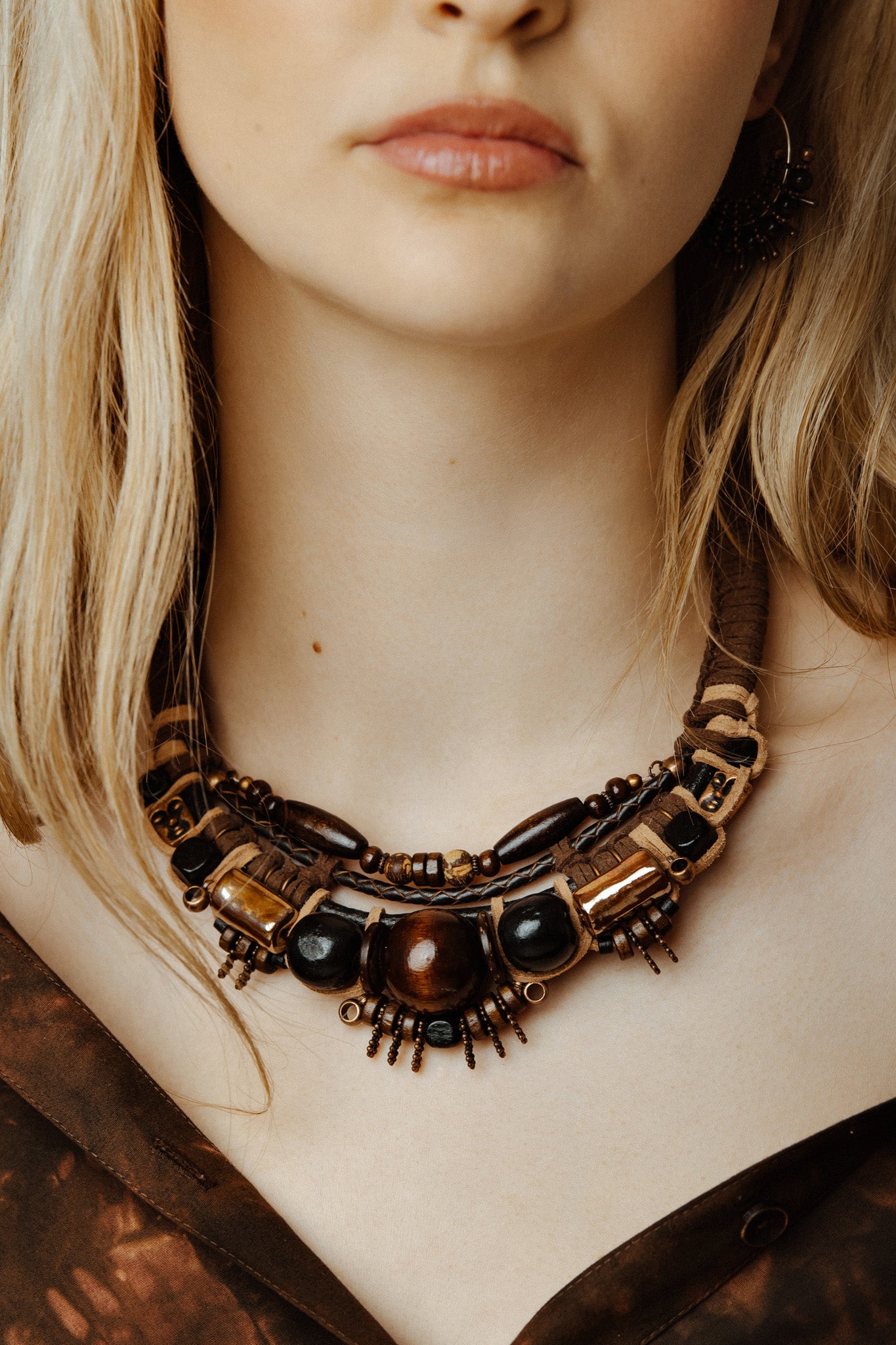 Close-up of a person wearing tribal gold face necklace with intricate design and dark beads.