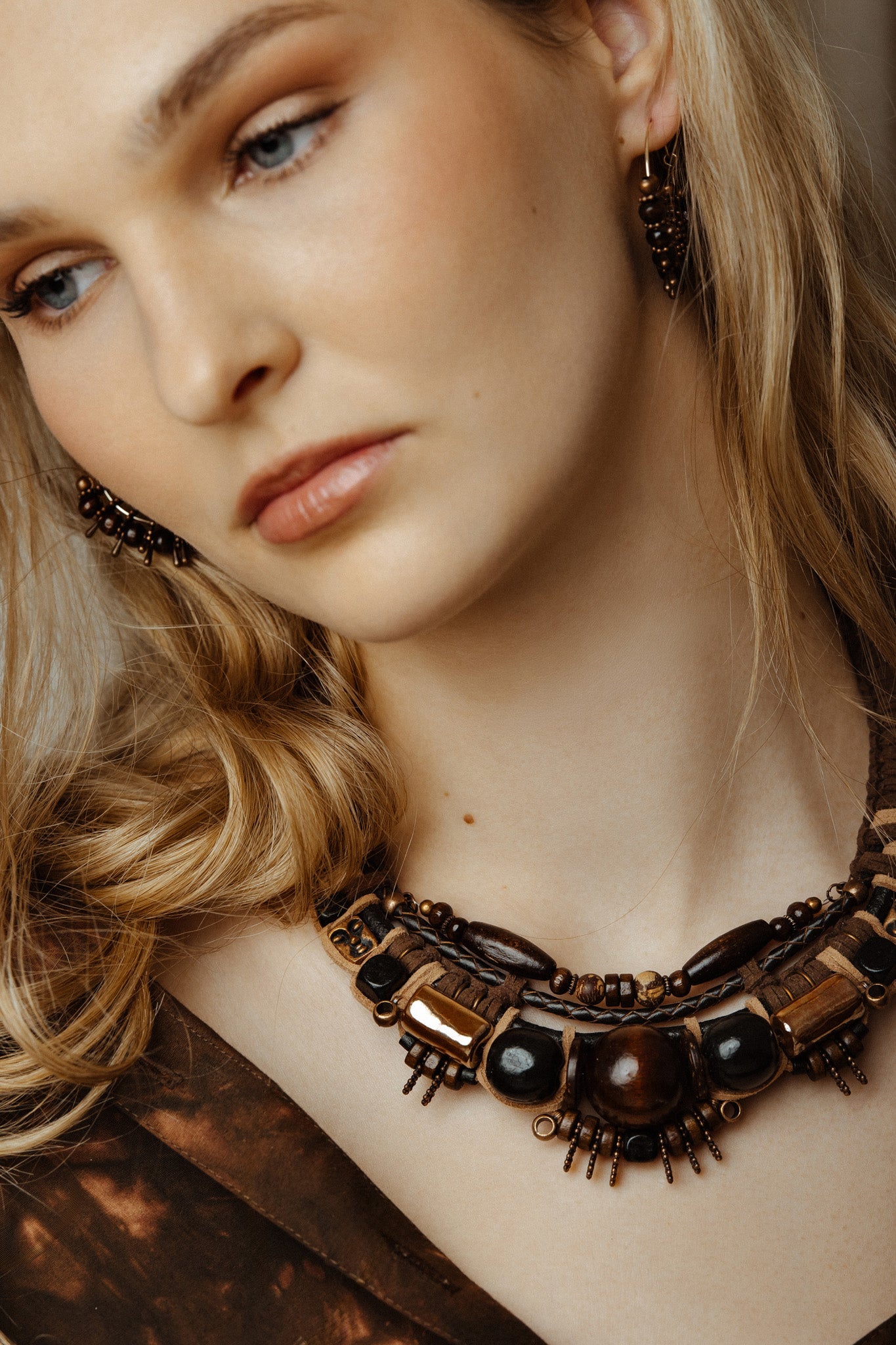 Close-up of a woman wearing tribal gold face necklace with a neutral background