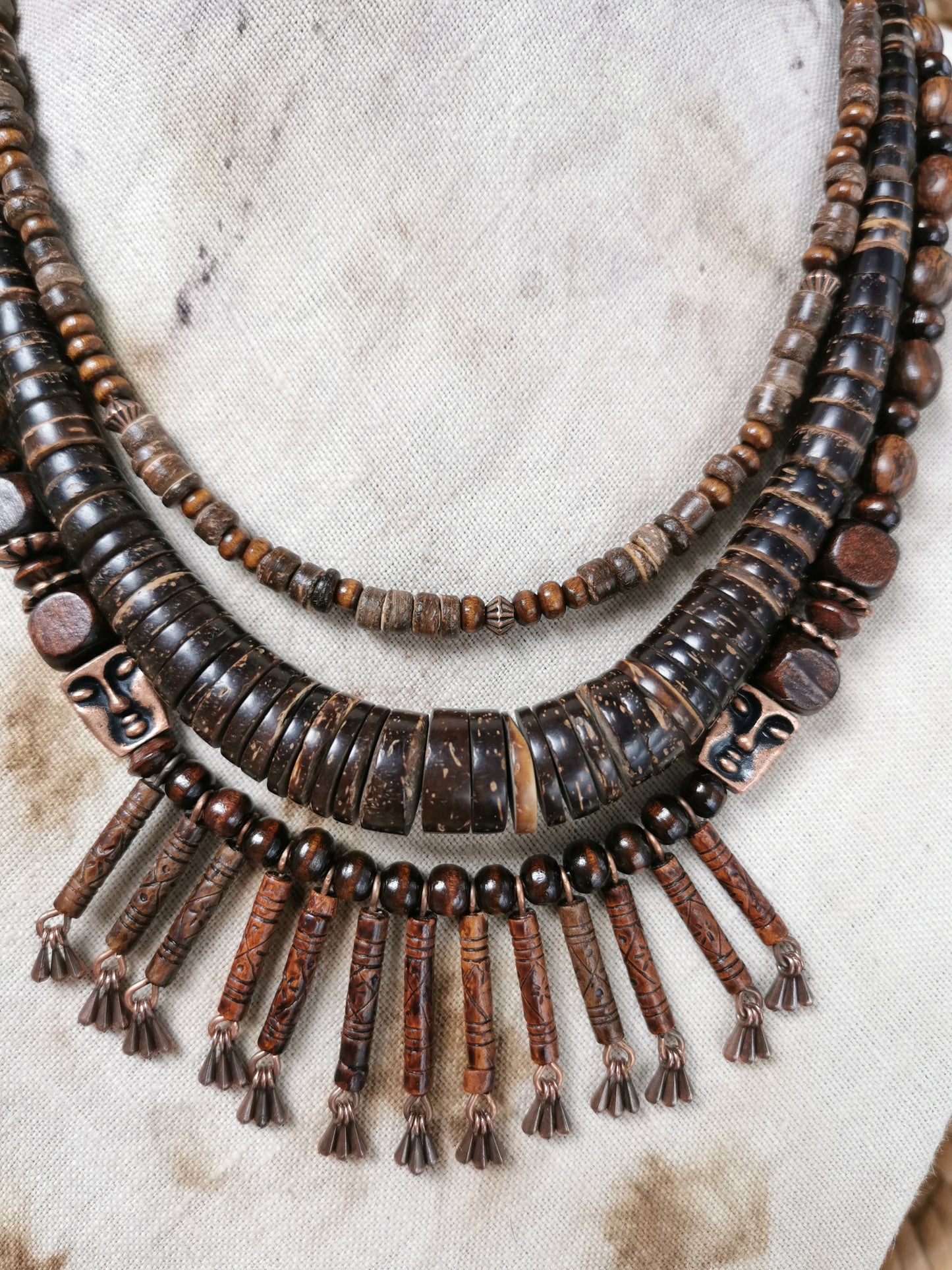 Brown beaded necklace with tassels on a textured beige background