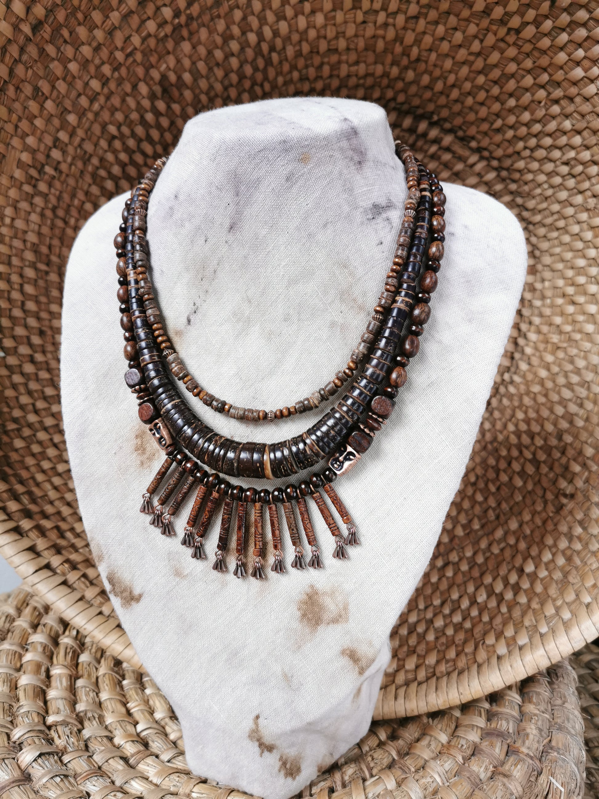 Necklace with brown beads on a white stone surface with a woven mat background
