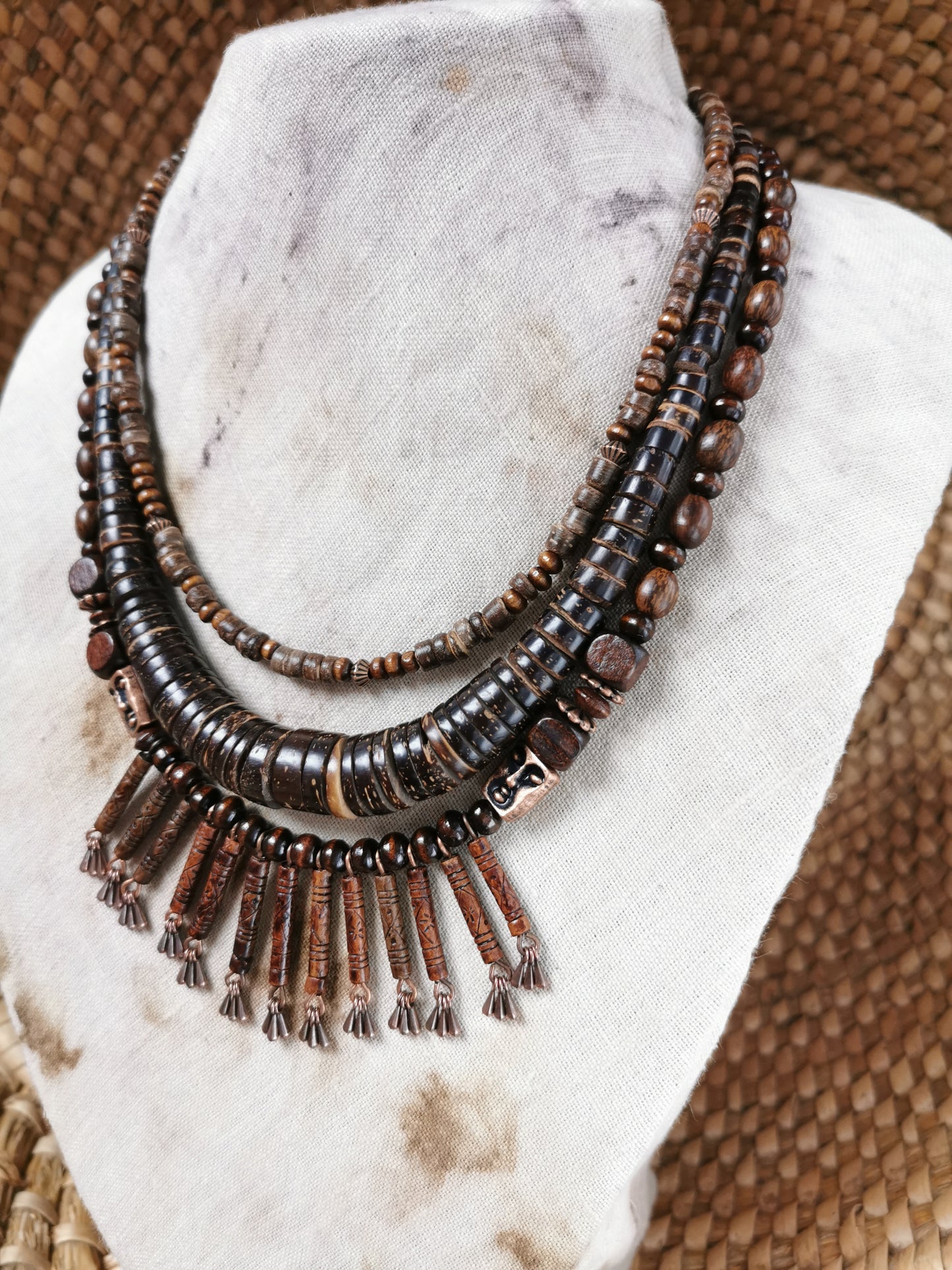 Necklace with brown beads and tassels on a marble stand