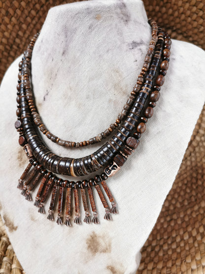 Necklace with brown beads and tassels on a marble stand