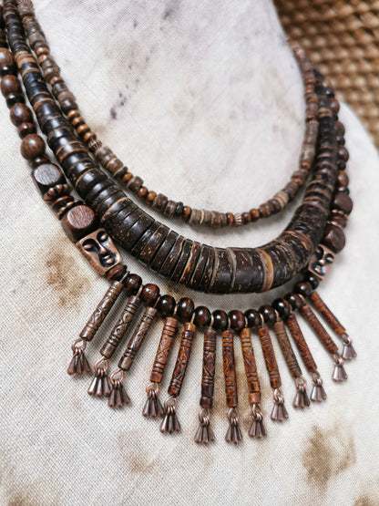 Brown beaded necklace with tassels on a textured fabric background