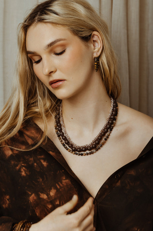 Woman wearing a necklace and earrings against a neutral background