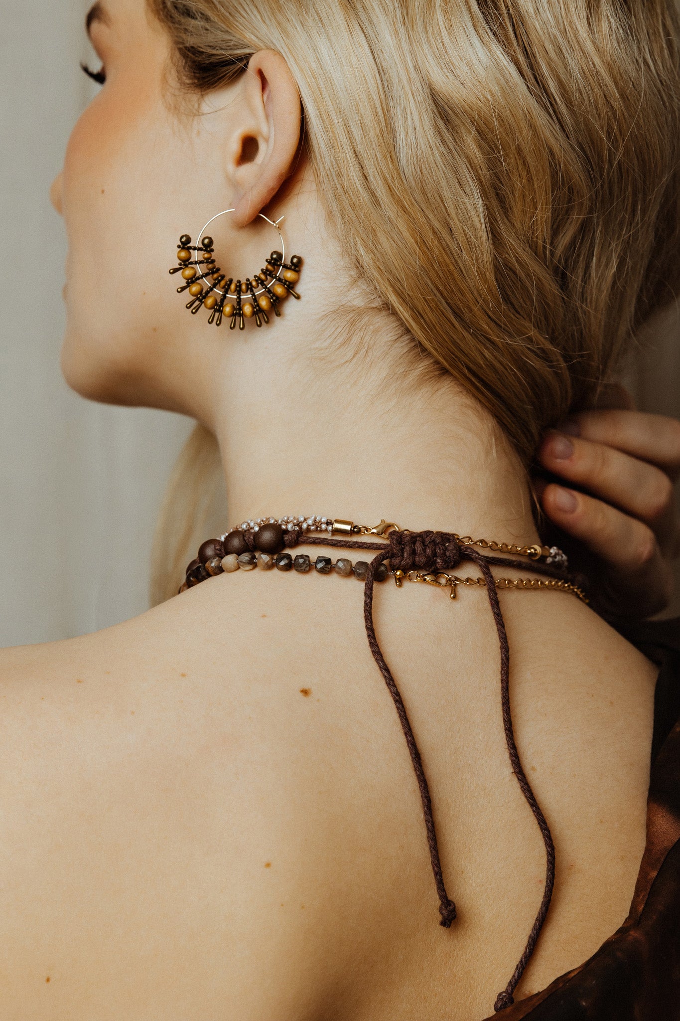 Close-up of a person wearing intricate jewelry including earrings and a necklace.