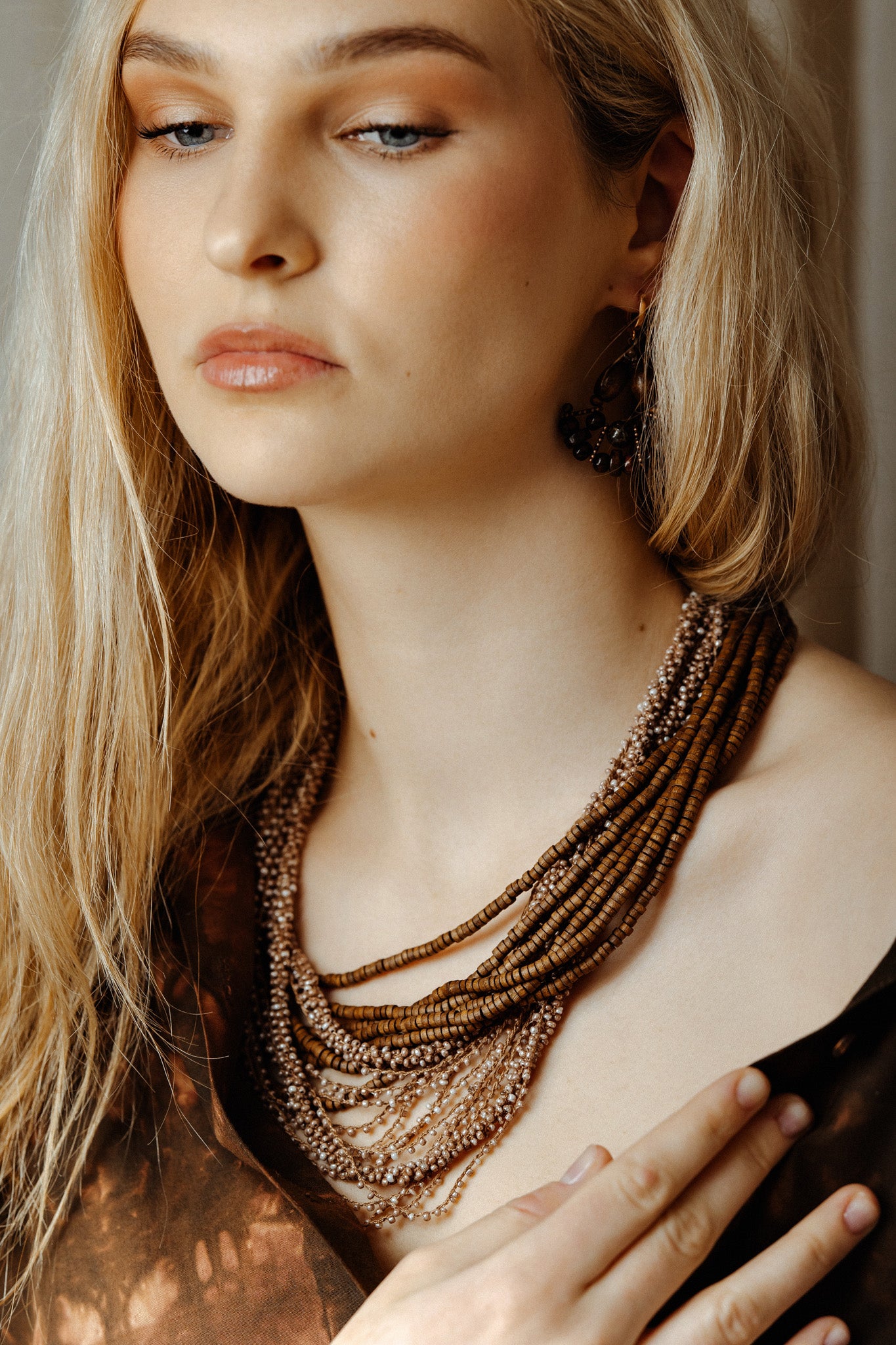 Woman wearing a layered necklace with a neutral background