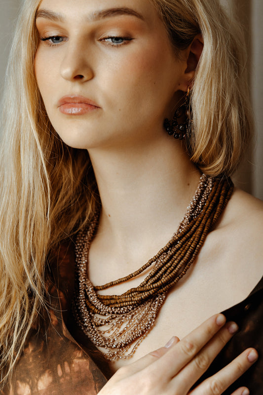 Woman wearing a layered necklace with a neutral background