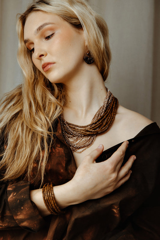 Woman wearing a textured necklace and earrings against a neutral background