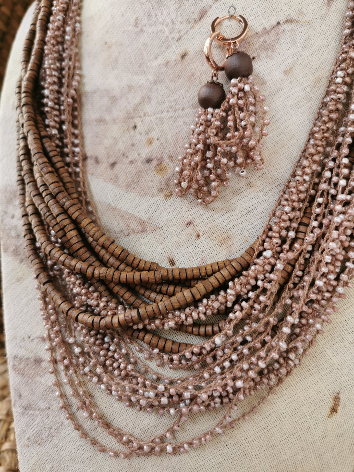 Necklace with multiple strands of beads and tassels on a textured surface