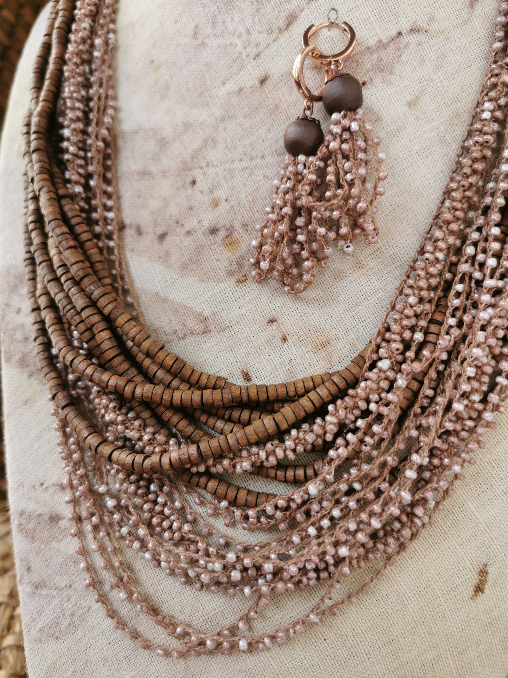 Necklace with multiple strands of beads and tassels on a textured surface