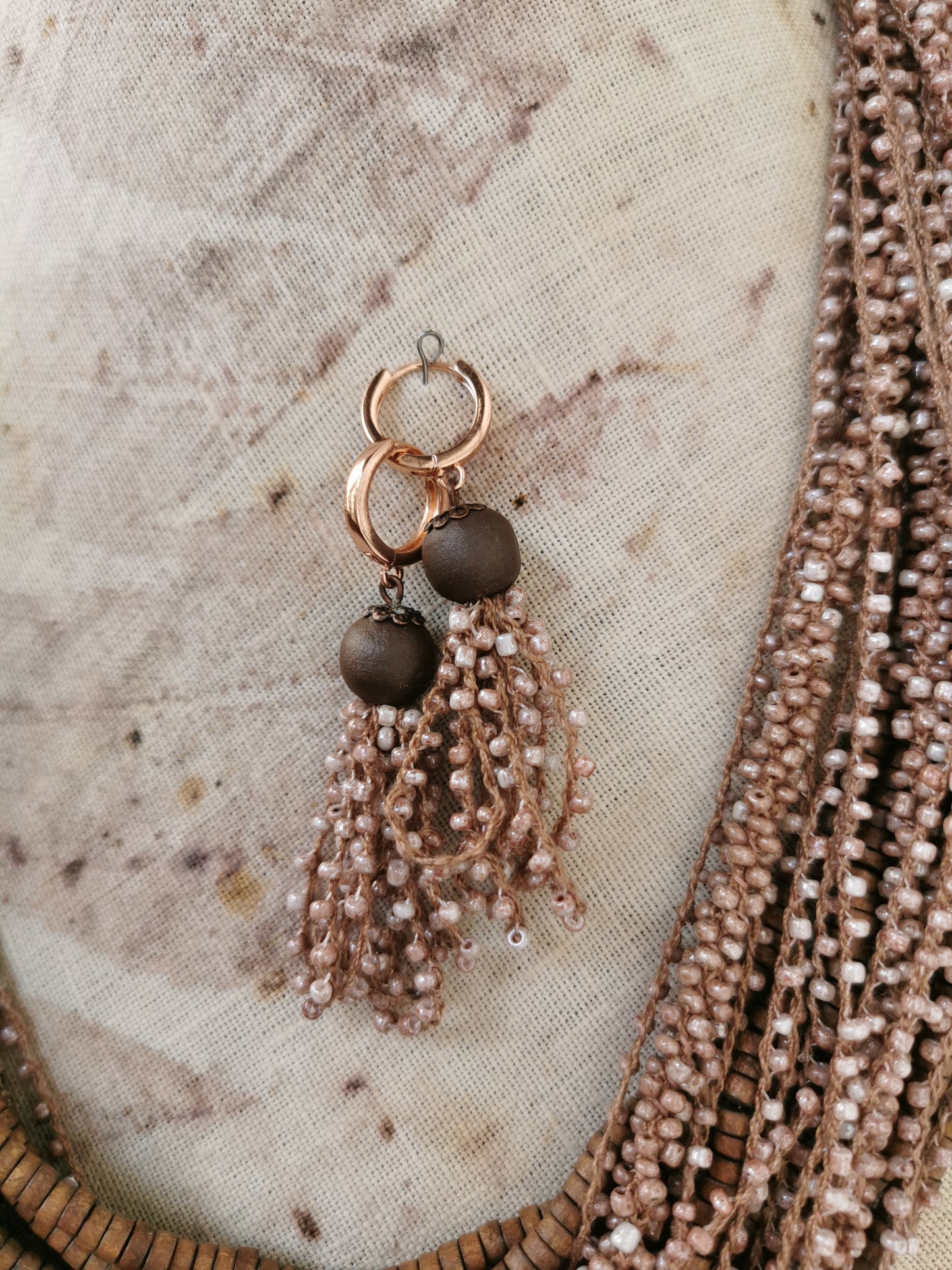 Earring with beads and tassels on a textured fabric background
